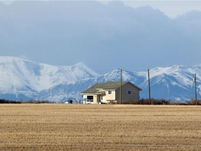 The Rockies rise behind a house on the Blood reserve.