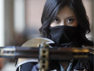 Diana Peng raises her bow at the Calgary Comic and Entertainment Expo Thursday April 16, 2015 just as the gates were opening. Decked out as Demon Hunter from the video game Diablo she had just passed the prop weapons checkpoint, a new requirement at this year's festival.