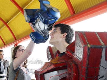 Optimist Prime Transformer, Taylor Nodrick, dons his helmet with help from girlfriend Kristin Jones while in line for the opening of the Calgary Comic and Entertainment Expo Thursday April 16, 2015 at the BMO Centre.