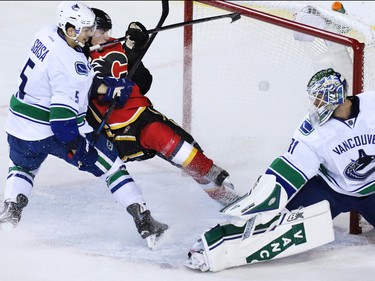 Sam Bennett and Vancouver's Luca Sbisa jostle as his shot goes past Canucks goaltender Eddie Lack during the first period of NHL playoff  game 4 action at the Scotiabank Saddledome. The goal was the Flames' third in the period.
