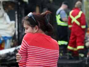 Laarni DeGuzman, a tenant in the upstair unit at 10772 Hidden Valley Drive N.W., looks at the gutted remains of her life while speaking with fire investigators on Tuesday, April 21, 2015.