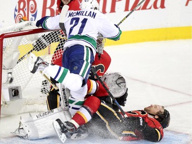 Calgary Flames Dennis Wideman, right, collides with Flames netminder Karri Ramo, middle and Vancouver Canucks Brandon McMillan during Game 6.