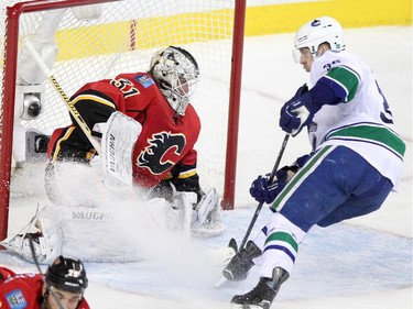 Calgary Flames netminder Karri Ramo, left, blocks Vancouver Canucks' Jannik Hansen's shot on net during Game 6.