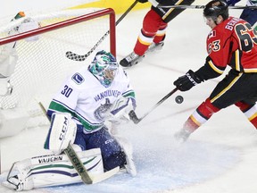 Vancouver Canucks netminder Ryan Miller, left, blocks a shot on net from Calgary Flames rookie Sam Bennett during Game 6 on Saturday night.