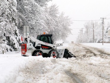 A bobcat tries to clean one of the major intersections of snow after as much as 40 cm of snow came down in Nanton over night with more snow coming down on Sunday morning on April 5, 2015.