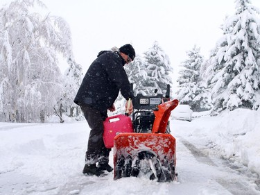 John-Paul Fawcett adds gas to a snow blower as he was getting to work clearing snowafter what looked like 40 cm of the white stuff came down in Nanton over night with more snow coming down on Sunday morning on April 5, 2015.