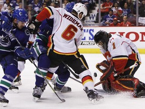 Goaltender Jonas Hiller and Dennis Wideman of the Calgary Flames make a stop against the Vancouver Canucks during Game 5 on Thursday night. The determined Canucks thoroughly outplayed the Flames and won 2-1.