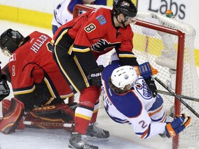 Edmonton Oilers Jeff Petry, right, collides into Calgary Flames Jonas Hiller's net as Joe Colborne collides into him during their game at the Scotiabank Saddledome  in Calgary on January 30, 2014.