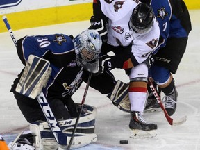 The Calgary Hitmen Pavel Karnaukhov fights for the pucks against Kootenay Ice goalie Wyatt Hoflin in Game 5 of the Western Hockey League playoff series at the Scotiabank Saddledome in Calgary on April 3, 2015.