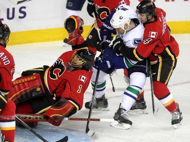 Calgary Flames goalie Jonas Hiller got twisted around on the ice as Vancouver Canucks centre Shawn Matthias and Flames defenceman Kris Russell battled outside the crease during first period NHL Game 3 playoff action at the Scotiabank Saddledome in Calgary on April 19, 2015. Matthias scored on the play.