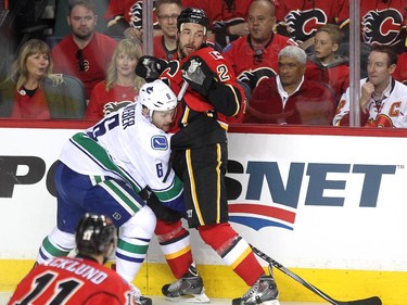Vancouver Canucks defenceman Yannick Weber got creatve reaching for the puck between the legs of Calgary Flames defenceman Deryk Engelland during first period NHL Game 3 playoff action at the Scotiabank Saddledome in Calgary on April 19, 2015.
