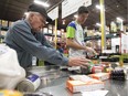 Calgary Food Bank volunteers Bob Allen, left, and Kyle Zerbin sort through donated food at the food bank on November 13, 2014 in preparation for distribution.  The organization is worried that a cut in the provincial tax credit will hurt financial donations to the food bank.