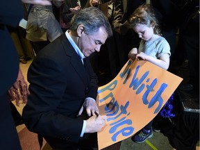 Alberta Premier Jim Prentice signs a little girl's sign as he arrives to call an provincial election at Crestwood Hall in Edmonton on Tuesday Apr. 7, 2015.