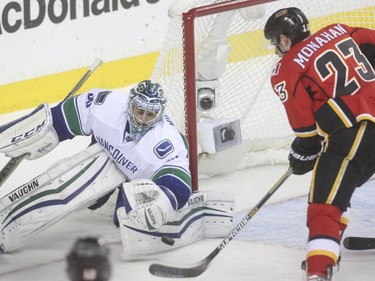 Calgary Flames centre Sean Monahan, right, takes a shot on Vancouver Canucks goalie Ryan Miller.