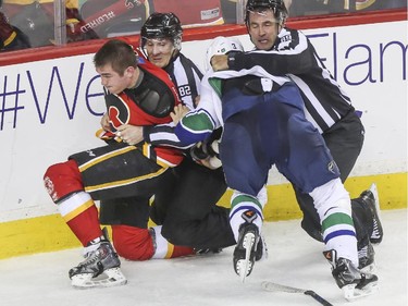 Calgary Flames Michael Ferland gets pulled away from Vancouver Canucks Kevin Bieksa during game three playoff action at the Saddledome in Calgary, on April 19, 2015.