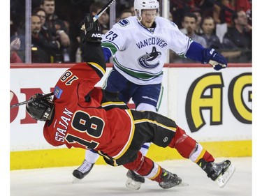 Calgary Flames Matt Stajan takes a crosscheck from Vancouver Canucks Alexander Edler during game three playoff action at the Saddledome in Calgary, on April 19, 2015.