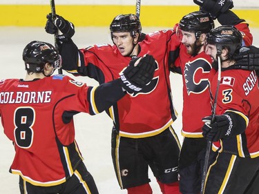 Calgary Flames Joe Colborne, from left, Mikael Backlund, TJ Brodie, and David Schlemko celebrate the Flames second goal against the Vancouver Canucks during playoff action at the Saddledome in Calgary, on April 19, 2015.