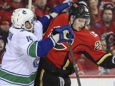 Calgary Flames Sean Monahan takes a shot to the face from Vancouver Canucks Brad Richardson during game three playoff action against the at the Saddledome in Calgary, on April 19, 2015.