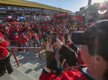 MJ MacKenzie, closest, and Jessica LaRoche, take pictures of the sea of red on the front steps of the Saddledome before the Flames first playoff home game in six years in Calgary, on April 19, 2015. -