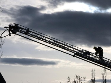 A firefighter heads back up the ladder against the evening sky at a large fire on Hidden Valley Drive N.W. on A home owner shows the emotion of seeing her home damaged by flames in a large fire on Hidden Valley Drive on April 20.