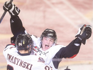 Calgary Hitmen defenceman Travis Sanheim, right, embraces Joe Mahon at the Scotiabank Saddledome in Calgary on Friday, April 17, 2015. The Calgary Hitmen won over the Medicine Hat Tigers, 4-3, in double overtime in the second round Western Hockey League play.