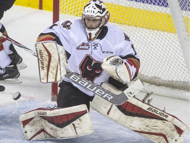 Calgary Hitmen goalie Brendan Burke eyes down a hard shot from the Brandon Wheat Kings during WHL playoff action at the Saddledome in Calgary, on April 28, 2015.