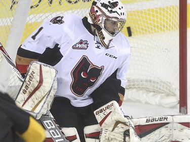 Calgary Hitmen goalie Brendan Burke turns in time to see a shot from the Brandon Wheat Kings fly by hime during WHL playoff action at the Saddledome in Calgary, on April 28, 2015.