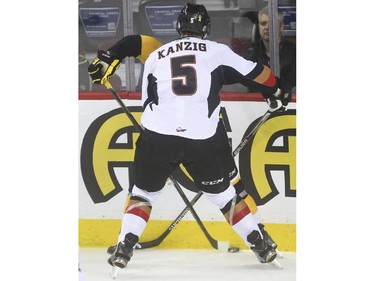 Calgary Hitmen's Keegan Kanzig mirrors Brandon Wheat Kings' Peter Quenneville into the boards during WHL playoff action at the Saddledome in Calgary, on April 29, 2015.