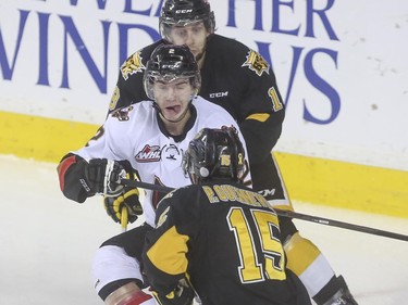 Calgary Hitmen's Jake Bean readies himself to be sandwiched between Brandon Wheat Kings' Morgan Klimchuk and Peter Quenneville during WHL playoff action at the Saddledome in Calgary, on April 29, 2015.