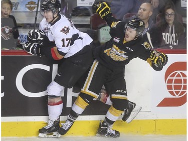 Brandon Wheat Kings Jayce Hawryluk gives Calgary Hitmen's Jordy Stallard a good hip check into the boards during WHL playoff action at the Saddledome in Calgary, on April 29, 2015.
