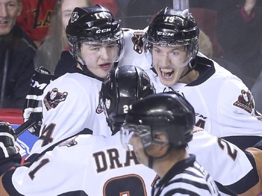 Calgary Hitmen Layne Bensmiller, left, Adam Tambellini, right, and Terrell Draude celebrate after scoring the first goal of the game against the Brandon Wheat Kings during WHL playoff action at the Saddledome in Calgary, on April 29, 2015.