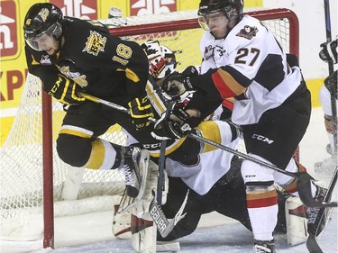 Brandon Wheat Kings' Morgan Klimchuk trips of Calgary Hitmens goalie Brendan Burke during WHL playoff action at the Saddledome in Calgary, on April 28, 2015.