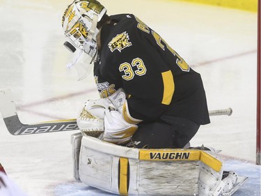 The pressure is on as Brandon Wheat Kings' goalie Jordan Papirny makes this save off his helmet during WHL playoff action at the Saddledome in Calgary, on April 28, 2015.