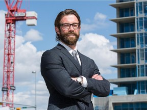 Ian Meredith, a residential expert with the  Altus Group, stands in front of two new condo developments in downtown Calgary on Tuesday May 13, 2014.