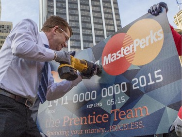Wildrose leader Brian Jean talks about his party's goal to end PC perks, then literally cuts an oversized PC "MasterPerks" credit card during a campaign announcement at the McDougall Centre in Calgary, on April 16, 2015.