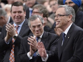 Minister of Finance Joe Oliver waves as he is given a standing ovation from his party as he arrives to deliver the federal budget in the House of Common on Parliament Hill in Ottawa on Tuesday, April 21, 2015.