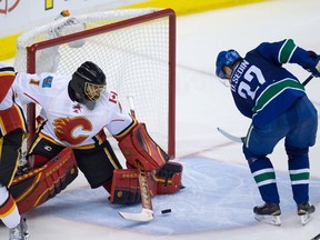 Vancouver Canucks' Daniel Sedin, right, of Sweden, scores against Calgary Flames' goalie Jonas Hiller, of Switzerland, during the third period of game 5 of an NHL Western Conference first round playoff hockey series in Vancouver, B.C., on Thursday April 23, 2015.