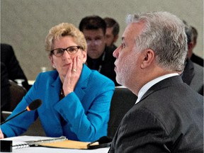 Quebec Premier Philippe Couillard, right, speaks at the beginning of a summit on climate change as Ontario Premier Kathleen Wynne, left, looks on, Tuesday, April 14, 2015 in Quebec City.