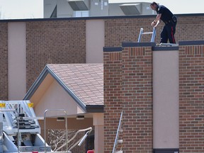 Lethbridge regional police service look for evidence on the roof of a nearby church while investigating a triple-homicide in Lethbridge, Alberta.   Police were called to a westside residence on McGill Blvd. at 2:30 am Tuesday, April 2015. The victims, one female and two males. were adults and known to police but no cause of death or what type of weapons were used is being released at this time.  Police believe the victims were targeted and say it was a violent scene. David Rossiter / Calgary Herald