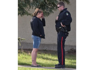 Lethbridge regional police service talk to a distraught neighbour whilea investigating a triple-murder in Lethbridge, Alberta.   Police were called to a westside residence on McGill Blvd. at 2:30 am Tuesday, April 2015. The victims, one female and two males. were adults and known to police but no cause of death or what type of weapons were used is being released at this time.  Police believe the victims were targeted and say it was a violent scene. David Rossiter / Calgary Herald