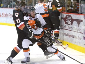 Medicine Hat Tigers forward Blake Penner and Calgary Hitmen centre Beck Malenstyn battle for the puck during Game 4 of their Western Hockey League playoff series on Wednesday night. Calgary won 2-1 in overtime to take a 3-1 series lead.