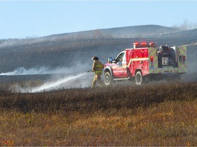 Calgary firefighters battle a grass fire in Nose Hill Park. Reader says there'd be fewer fires if smokers would quit tossing their butts onto the roads.