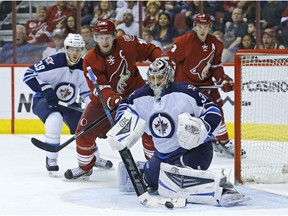 Phoenix Coyotes right wing Shane Doan (19) looks for a rebound as Winnipeg Jets goalie Ondrej Pavelec (31) makes a save during the first period of an NHL hockey game Tuesday, April 1, 2014, in Glendale, Ariz.