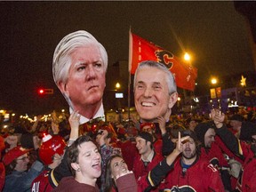 Calgary Flames fans hold up cut out heads of Brian Burke, left, and Bob Hartley walk on 17th Ave SW, aka. The Red Mile, after the Flames beat the Canucks in game six of the playoff's in Calgary, on April 25, 2015.