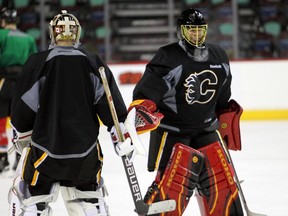 Calgary Flames goalie Jonas Hiller bumps gloves with recent AHL call-up Brad Thiessen during practice on Monday.
