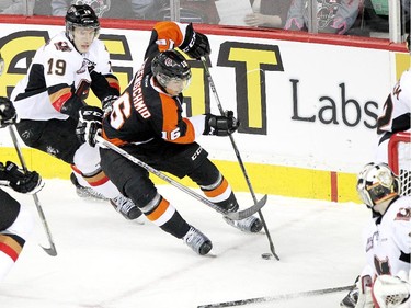 Medicine Hat Tigers' Markus Eisenschmid keeps the puck away from Calgary Hitmen star Adam Tambellini in  Game 2 on Sunday. The Tigers won 3-2 in overtime.