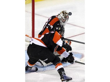 CALGARY, ; APRIL 12, 2015  --Tigers goalie Marek Langhamer stops the puck with his head, and teammate Tyler Lewington in the first period which was scoreless in game two as the Calgary Hitmen played host to the Medicine Hat Tigers at the Saddledome on April 12, 2015. (Lorraine HJalte/Calgary Herald) For Sports story by . Trax # 00064111A