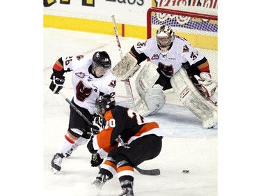 CALGARY, ; APRIL 12, 2015  --Hitmen goalie Mack Shields gets some help in front of the net from Elliot Peterson, 28, while Tigers Anthony Ast tries to get puck in the net  in game two as the Calgary Hitmen played host to the Medicine Hat Tigers at the Saddledome on April 12, 2015. (Lorraine HJalte/Calgary Herald) For Sports story by . Trax # 00064111A