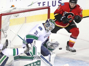 Calgary Flames centre Mikale Backlund kept an eye on the puck as Vancouver Canucks goalie Eddie Lack stopped it during second period NHL Game 3 playoff action at the Scotiabank Saddledome in Calgary on April 19, 2015.