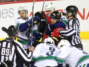 The bad blood between the two teams continued into Game 3 as Calgary Flames centre Matt Stajan, centre, got held up by Vancouver Canucks centre Shawn Matthias (27) and other members of the Canucks during second period NHL Game 3 playoff action at the Scotiabank Saddledome in Calgary on April 19, 2015.